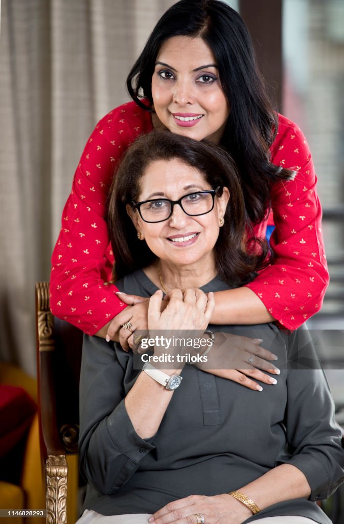 Vrouw omarmen Senior moeder van achter