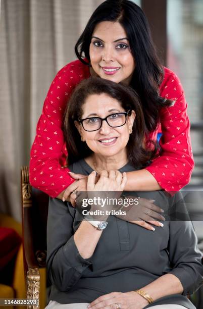 woman embracing senior mother from behind - indian mother daughter stock pictures, royalty-free photos & images