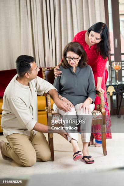 couple taking care of mother suffering with knee pain - son massage mom imagens e fotografias de stock