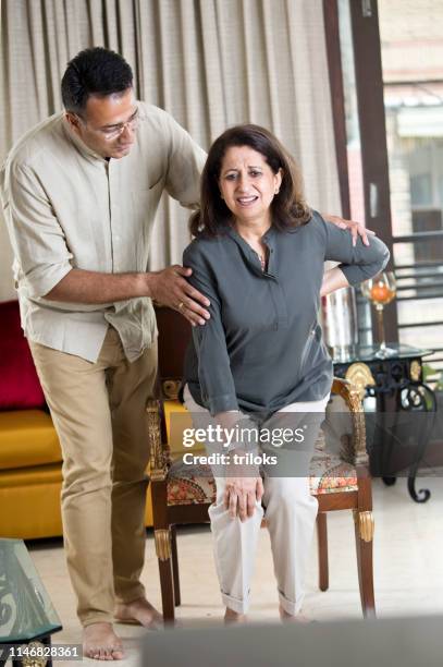 man taking care of mother suffering with knee pain - knee stock pictures, royalty-free photos & images