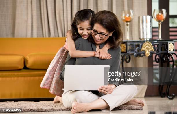 grandmother with granddaughter using laptop at home - granddaughter stock pictures, royalty-free photos & images