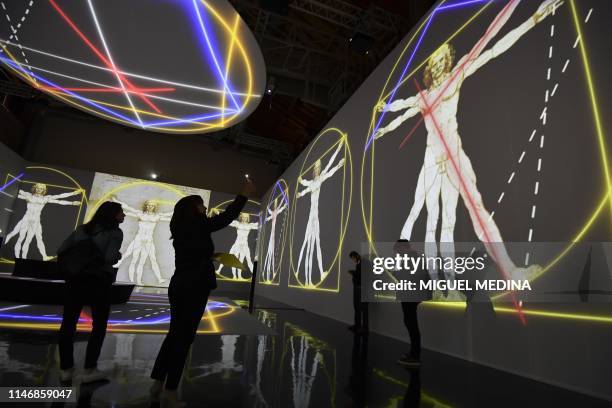 People watch a hologram of "L'uomo vitruviano" during the Leonardo da Vinci multimedia installation "Leonardo Da Vinci 3D" at the Fabbrica del Vapore...