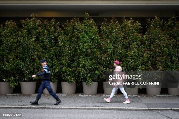 People walks past the entrance of The Fairmont Le Montreux Palace hotel hidden by plants in Montreux on May 29 which is scheduled to host the annual...