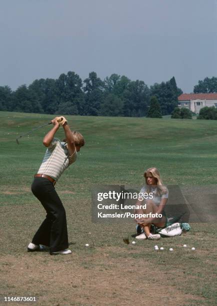 American golfer Ben Crenshaw takes some practice shots, watched by his wife Polly, circa 1976.