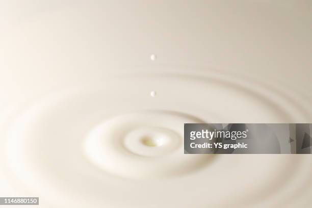 fresh milk single drop splashing in a milk pool. white background. with circle ripples. - cream splash stockfoto's en -beelden