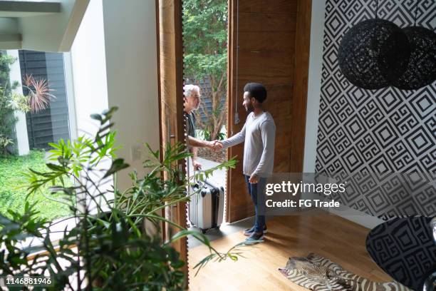 host welcoming his guest in the entrance hall - house rental stock pictures, royalty-free photos & images