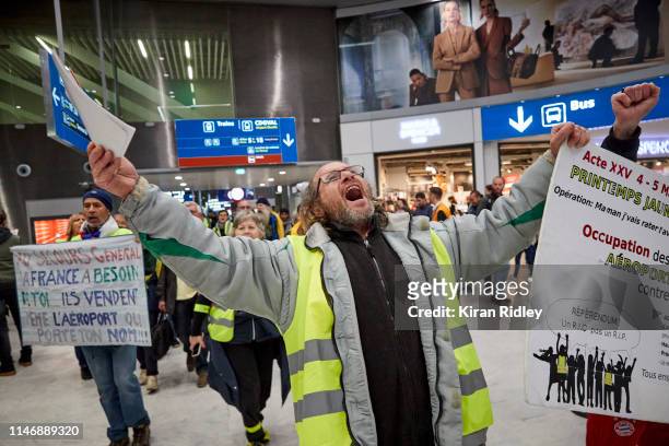 Gilets Jaunes or 'Yellow Vest' protestors chant for the resignation of President Macron as they march through Charles de Gaulle Airport demonstrating...