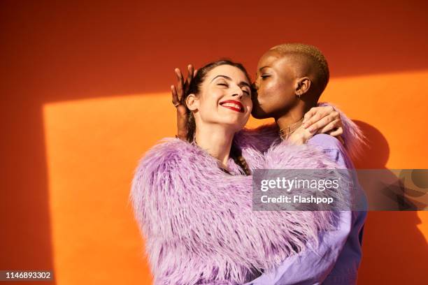 colourful studio portrait of two women - contact color background stock-fotos und bilder