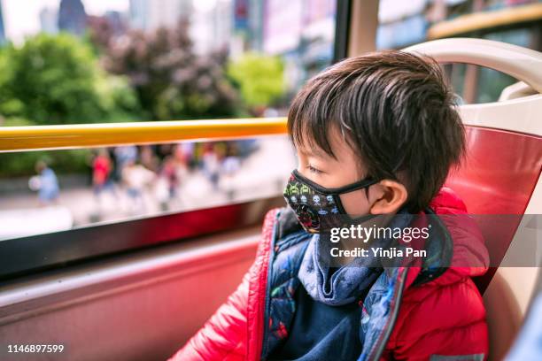 portrait of a little boy wearing protective face mask sitting on sightseeing bus, people's square, huangpu district, shanghai, china - chinese mask stockfoto's en -beelden