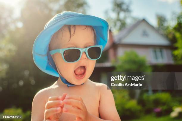 bambino carino con occhiali da sole nel cortile sul retro in estate - cappello per il sole foto e immagini stock