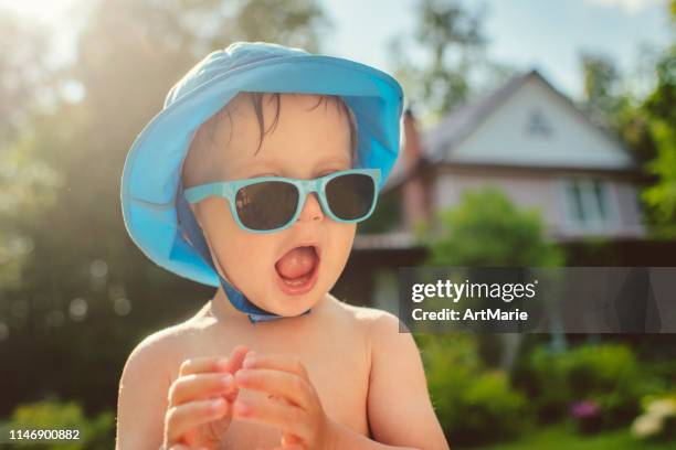 schattige kleine jongen met een zonnebril op achtertuin in de zomer - zonnehoed stockfoto's en -beelden