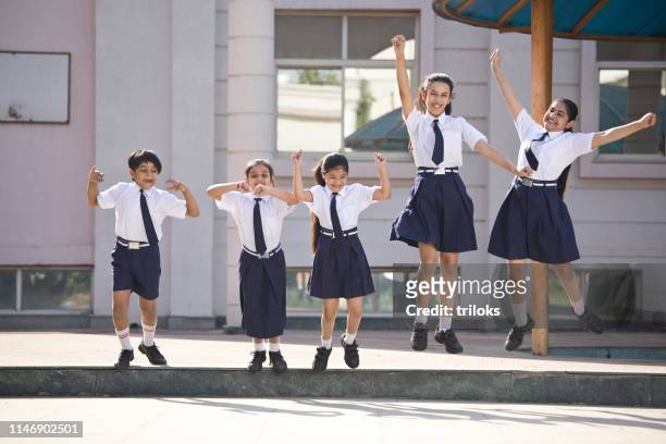school children jumping and celebrating in school campus - education stock pictures, royalty-free photos & images