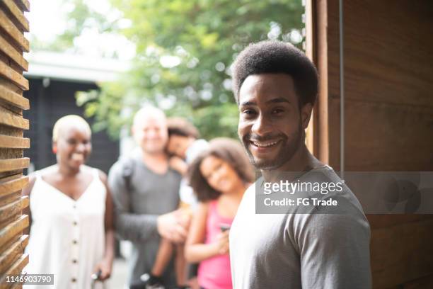 portrait of home owner welcoming family to rental house during vacation - diversity showcase arrivals stock pictures, royalty-free photos & images