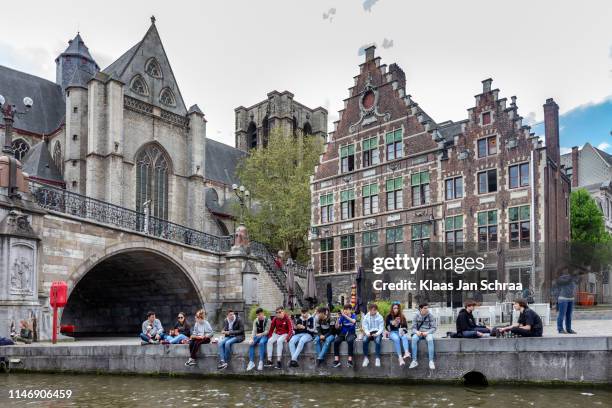 een menigte van studenten zittend aan de oever van de dijk graslei in het historische centrum van gent - gent stockfoto's en -beelden