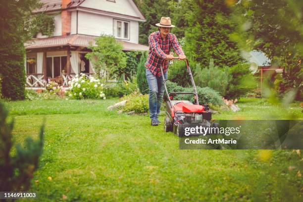 man using a lawn mower in his back yard - cortar relva imagens e fotografias de stock
