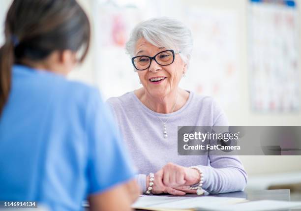 happy senior woman at doctor's office - pharmacist and patient stock pictures, royalty-free photos & images