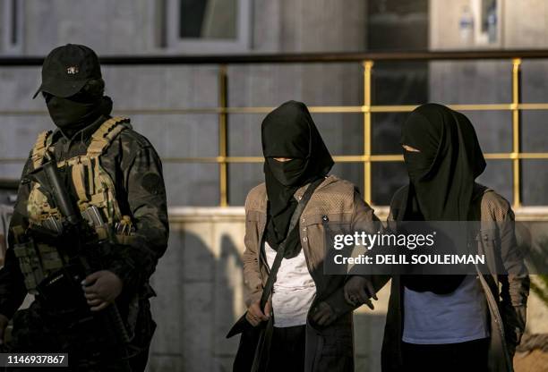 Fully veiled women walk in the northern Kuridish-Syrian city of Qamishli as Uzbek women and children linked to the Islamic State group are handed...