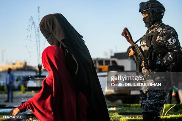 Backed Syrian Democratic Forces escort a fully veiled woman and a child in the northern Kuridish-Syrian city of Qamishli as Uzbek women and children...