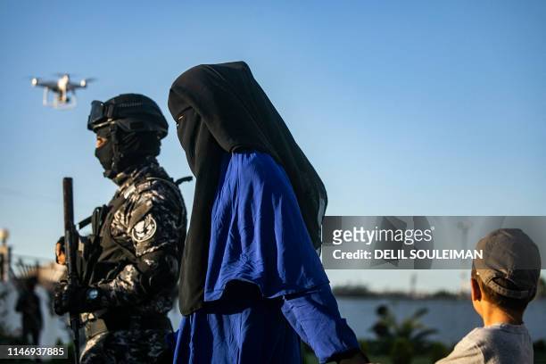 Backed Syrian Democratic Forces escort a fully veiled woman and a child in the northern Kuridish-Syrian city of Qamishli as Uzbek women and children...