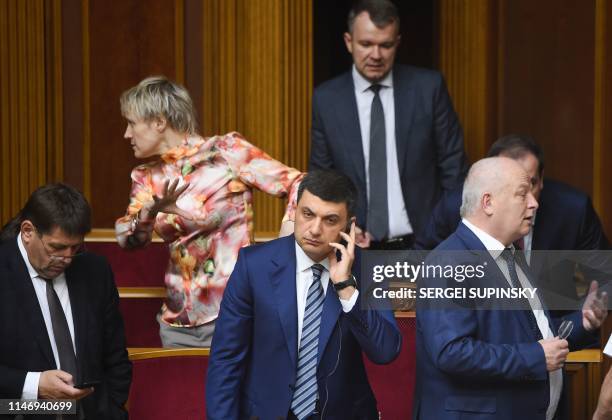 Ukrainian Prime Minister Volodymyr Groysman talks on the phone next members of his government following a vote over his resignation during a hearing...