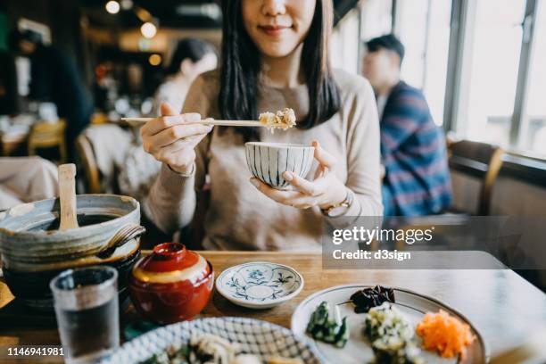 close up shot of smiling young woman enjoying japanese cuisine with various side dishes, miso soup and green tea in restaurant - prefectura de fukuoka fotografías e imágenes de stock