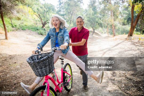mari poussant femme sur le vélo - couple de vieux drole photos et images de collection