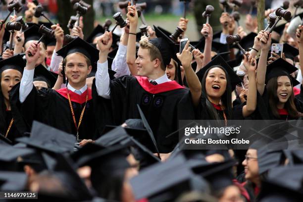 Law school graduates hold gavels aloft during the 2019 Harvard University commencement on Harvard Yard in Cambridge, MA on May 30, 2019.