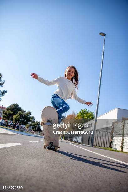 skateboarding young girl on city streets - wheelie stock pictures, royalty-free photos & images