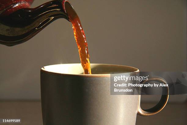 cup of tea being poured from brown teapot - tea cup photos et images de collection