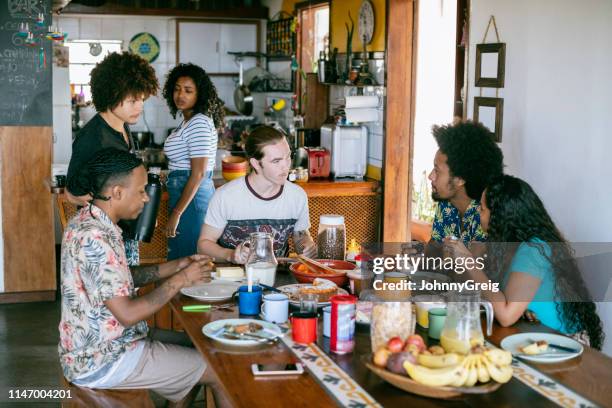 group people eating food in communal kitchen at guesthouse - casa interior stock pictures, royalty-free photos & images