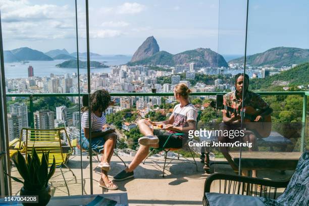 three friends on balcony with views of sugarloaf mountain - hostel people travel stock pictures, royalty-free photos & images