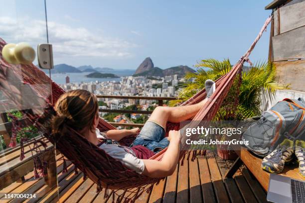 mann in hängematte auf balkon mit blick auf rio de janeiro - brazil ocean stock-fotos und bilder