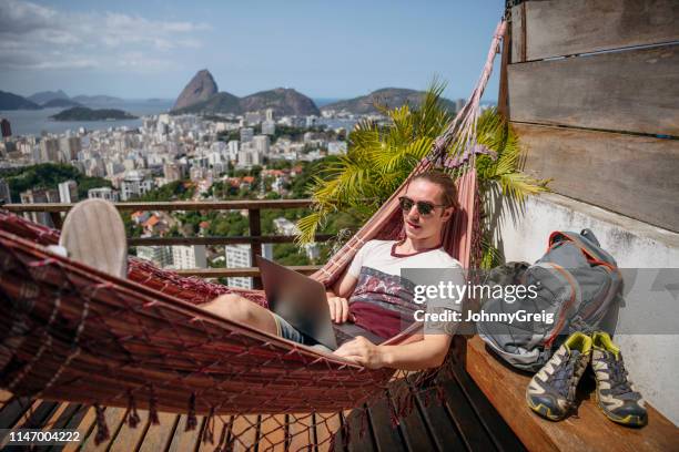 backpacker met behulp van laptop in hangmat op balkon in rio de janeiro - sabbatical stockfoto's en -beelden