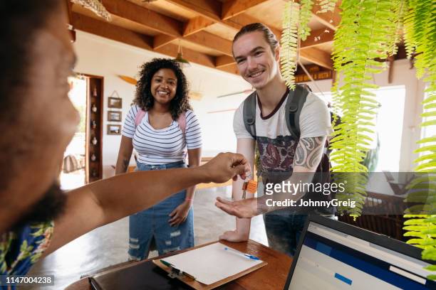 jeune homme avec la copine recevant des clefs à l’arrivée à la maison d’hôtes - auberge de jeunesse photos et images de collection