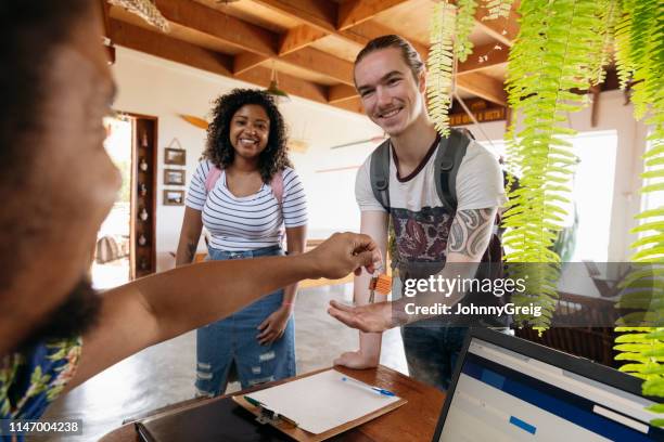 young man with girlfriend receiving keys on arrival at guesthouse - pousada de juventude imagens e fotografias de stock