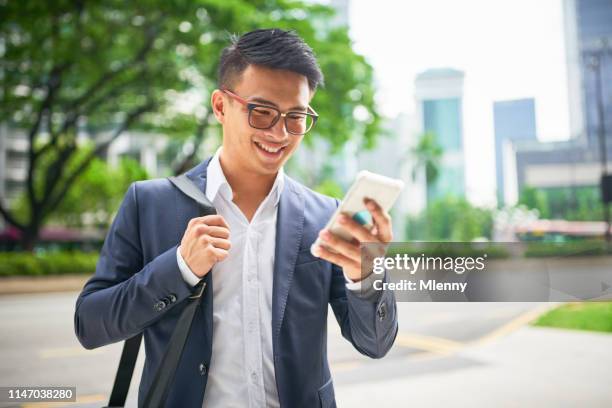 junger malaysischer geschäftsmann auf smartphone - chinese businessman stock-fotos und bilder