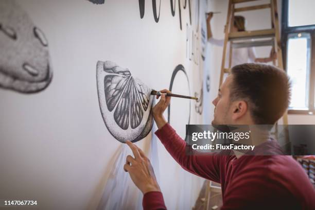 knappe kunstenaar schilderij op de muur - muurschildering stockfoto's en -beelden