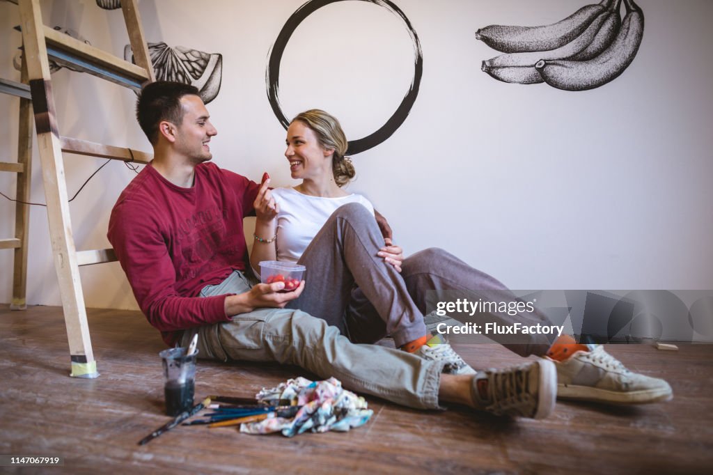Lovely couple taking a break from illustrating their new apartment