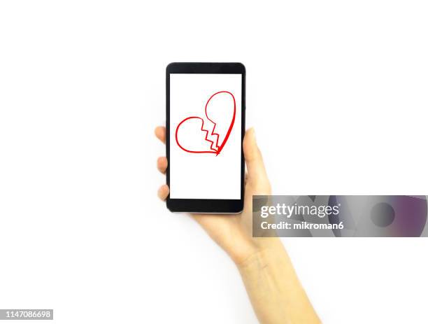 hand holding a phone with a broken heart on it - broken heart stock pictures, royalty-free photos & images