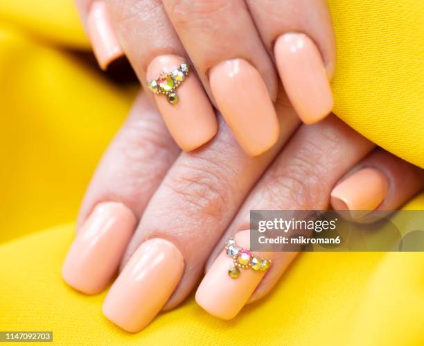 close-up of woman fingers with nail art manicure with nude colour - nagelkunst stockfoto's en -beelden