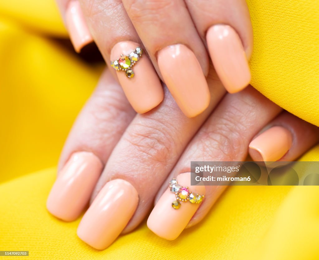 Close-Up Of Woman Fingers With Nail Art Manicure with nude colour