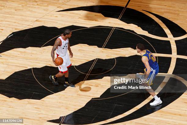 Kawhi Leonard of the Toronto Raptors dribbles the ball up court while guarded by Klay Thompson of the Golden State Warriors during Game One of the...