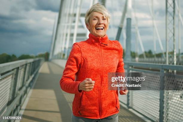 happy athletic senior woman running - senior women jogging stock pictures, royalty-free photos & images