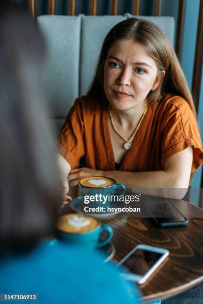 concerned young woman talks with friend in coffee shop - two people talking serious stock pictures, royalty-free photos & images