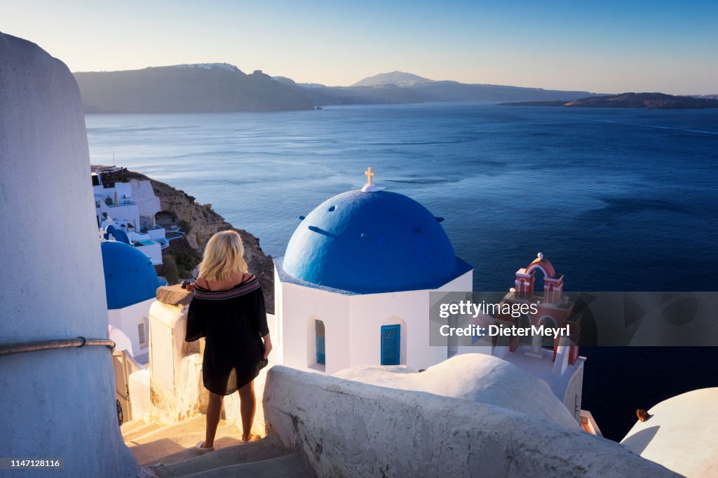 La mujer joven mira el paisaje marino, Santorini, Oia, Grecia