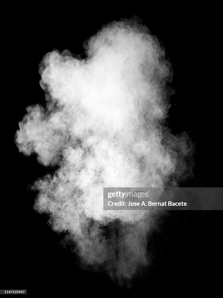 Explosion by an impact of a cloud of particles of powder and smoke of color white on a black  background.