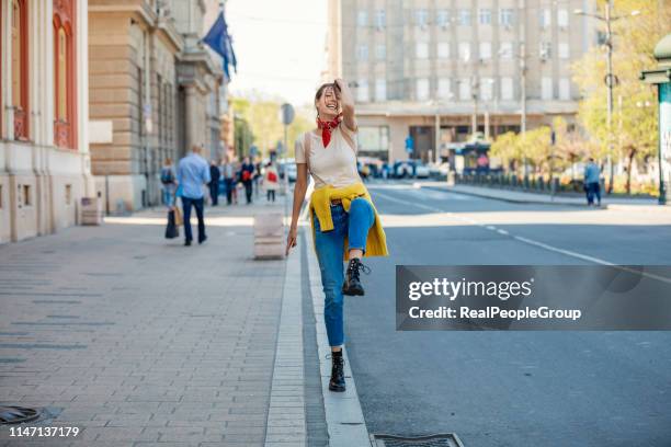 jovencita caminando por la carretera de la ciudad - woman cross legs fotografías e imágenes de stock