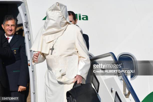 Gale of wind lifts Pope Francis' cassock upon his face as he boards a plane upon his departure for a three-day trip to Romania, on May 31, 2019 at...