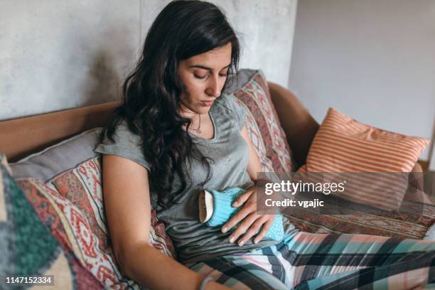 junge frau krank zu hause - wärmflasche stock-fotos und bilder