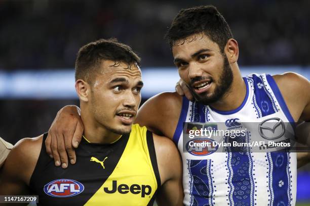 Sydney Stack of the Tigers is seen with Tarryn Thomas of the Kangaroos while players stand together against racism during the 2019 AFL round 11 match...